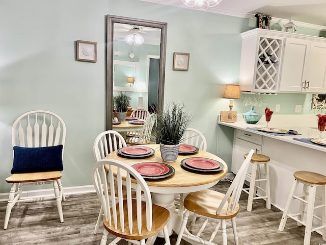 dining area with baseboards, light wood-style flooring, bar area, and a ceiling fan