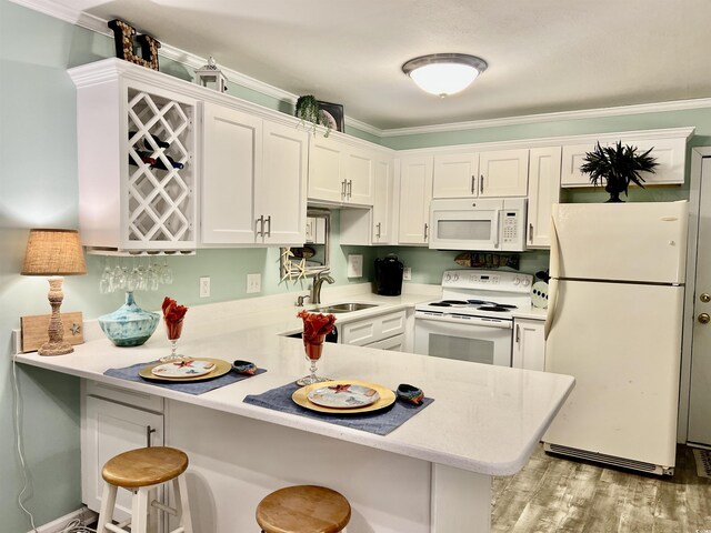 kitchen featuring light countertops, white cabinets, a peninsula, and white appliances