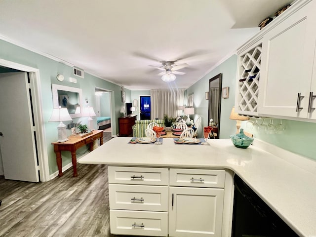 kitchen featuring crown molding, visible vents, light wood-style floors, ceiling fan, and a peninsula