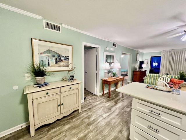 kitchen with light countertops, visible vents, ornamental molding, and light wood finished floors