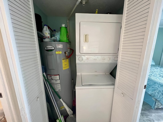 laundry room featuring water heater, stacked washer / drying machine, and laundry area