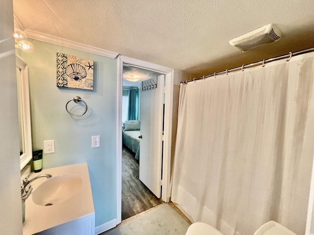 full bathroom featuring crown molding, curtained shower, vanity, wood finished floors, and a textured ceiling