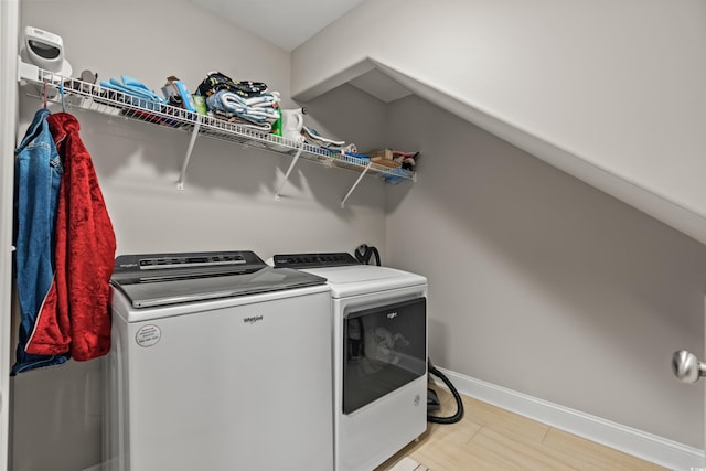 washroom with washing machine and clothes dryer and light hardwood / wood-style floors