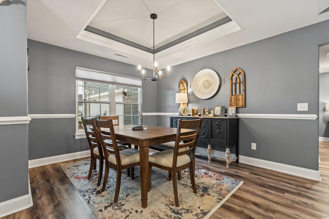 dining room featuring a notable chandelier, ornamental molding, a tray ceiling, and dark hardwood / wood-style flooring