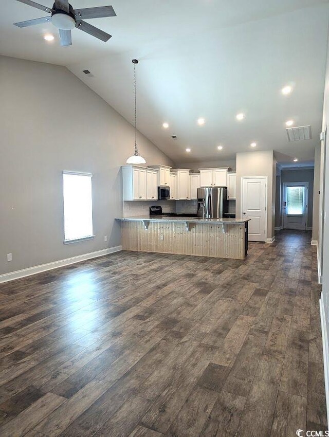 kitchen featuring appliances with stainless steel finishes, a breakfast bar area, hanging light fixtures, and white cabinets