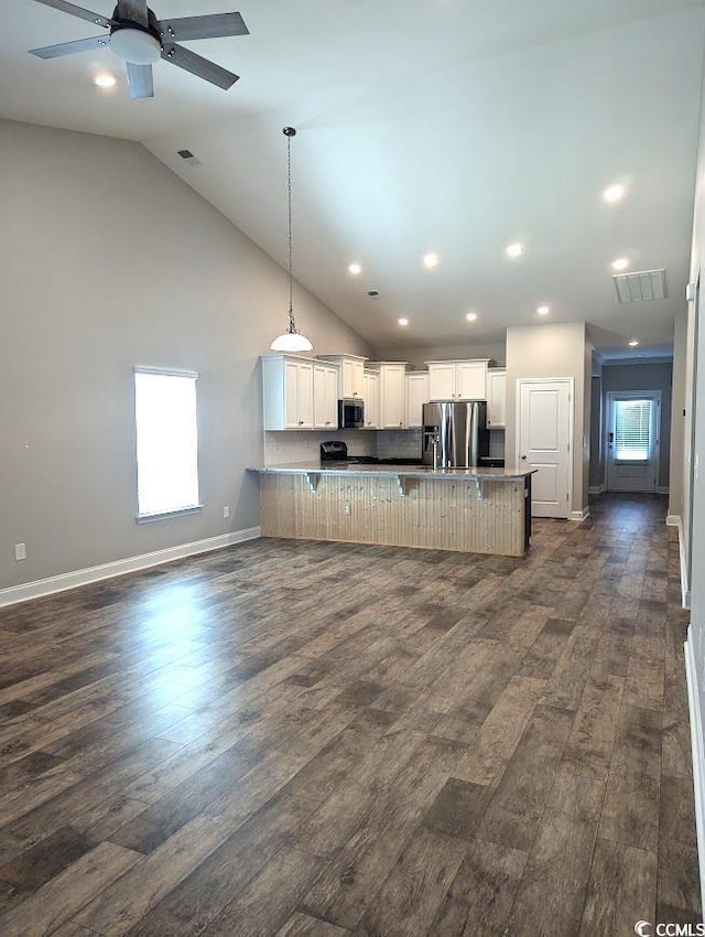 kitchen featuring a breakfast bar, dark wood-style flooring, visible vents, appliances with stainless steel finishes, and open floor plan