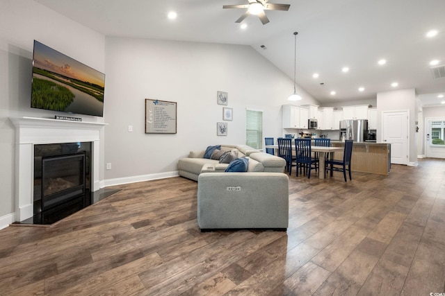 living room featuring dark wood finished floors, a fireplace, recessed lighting, high vaulted ceiling, and baseboards