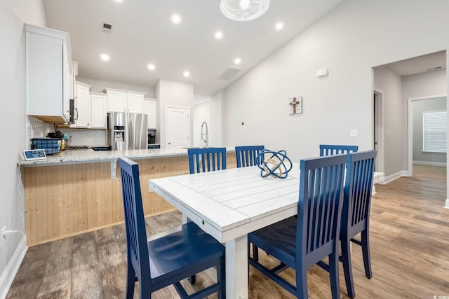 dining area with vaulted ceiling and light hardwood / wood-style floors