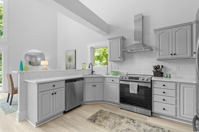 kitchen featuring sink, gray cabinets, stainless steel appliances, a towering ceiling, and light hardwood / wood-style floors