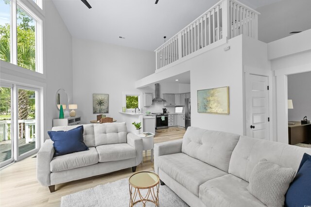 living room featuring ceiling fan, light hardwood / wood-style floors, and high vaulted ceiling