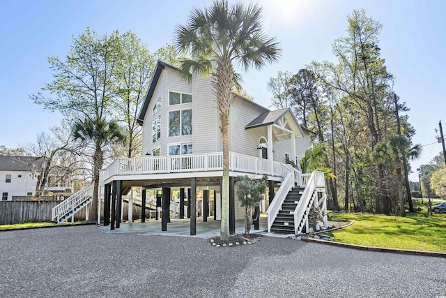 coastal inspired home featuring a carport, stairway, a front yard, and driveway