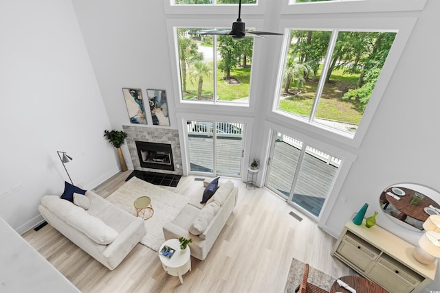 living room with light hardwood / wood-style flooring, plenty of natural light, a high ceiling, and a tile fireplace