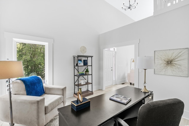 office area featuring light hardwood / wood-style flooring, a chandelier, and high vaulted ceiling