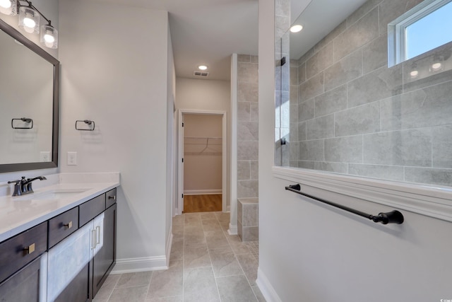 bathroom with tiled shower, vanity, and tile patterned floors