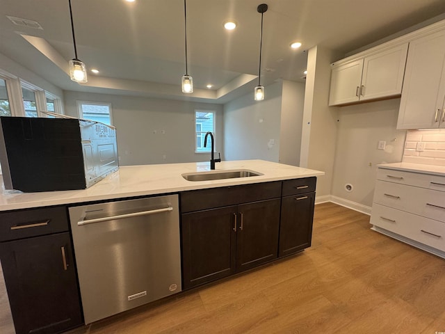 kitchen featuring sink, white cabinetry, hanging light fixtures, stainless steel dishwasher, and a raised ceiling