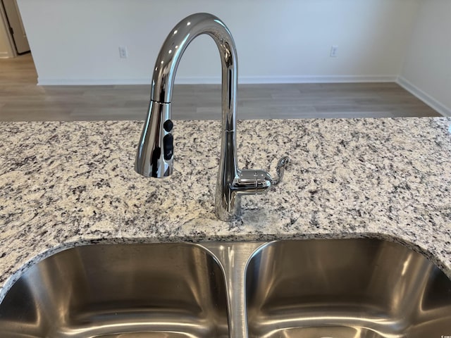 interior details with light stone countertops, hardwood / wood-style floors, and sink