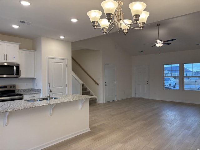 kitchen with stainless steel appliances, pendant lighting, light hardwood / wood-style floors, a breakfast bar area, and white cabinets