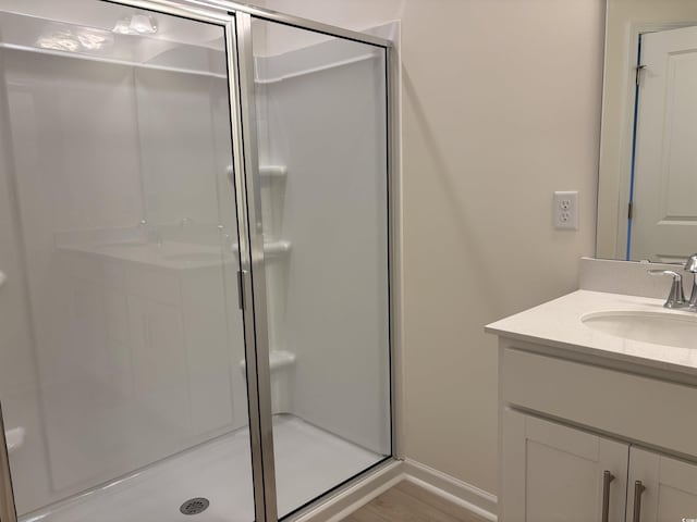 bathroom featuring a shower with door and vanity