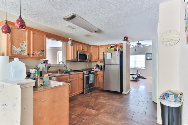 kitchen featuring ceiling fan, sink, kitchen peninsula, decorative light fixtures, and stainless steel appliances