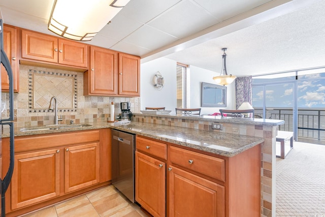 kitchen with hanging light fixtures, kitchen peninsula, tasteful backsplash, dishwasher, and light stone countertops