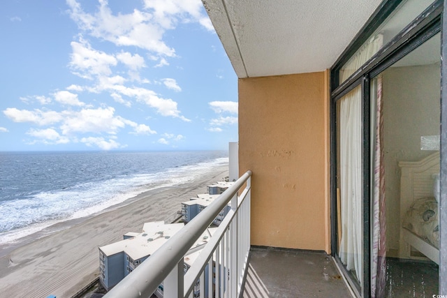 balcony featuring a view of the beach and a water view