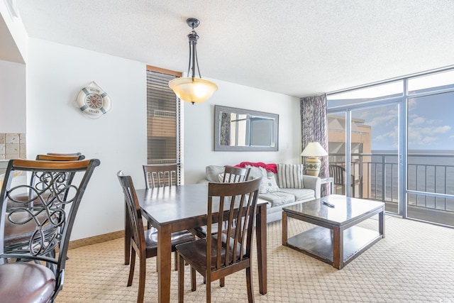 dining area featuring a textured ceiling, a water view, light carpet, and expansive windows