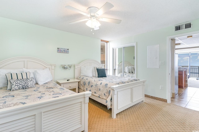 bedroom with ceiling fan, a textured ceiling, and light tile patterned floors