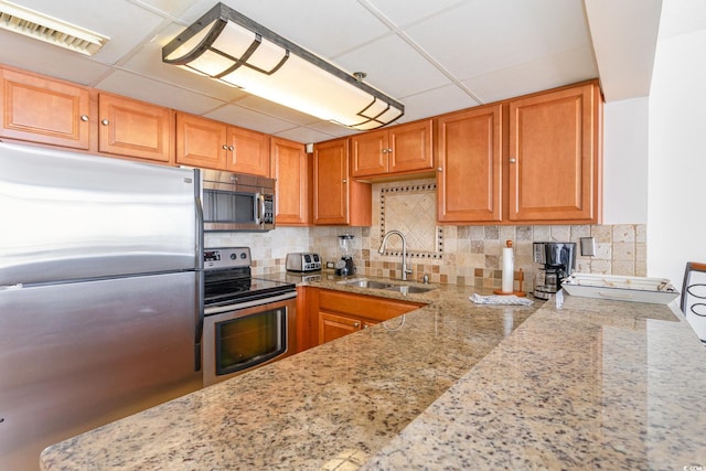 kitchen with light stone counters, sink, tasteful backsplash, a paneled ceiling, and appliances with stainless steel finishes