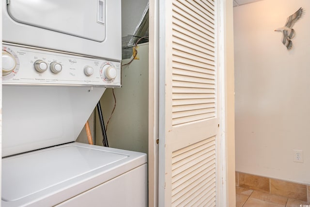 laundry room featuring stacked washer / dryer and light tile patterned flooring