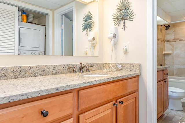 full bathroom with vanity, stacked washer / dryer, toilet, and tile patterned flooring