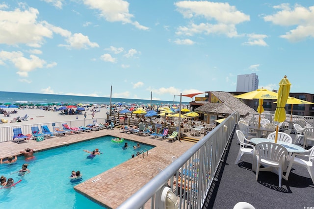 view of pool featuring a water view and a beach view