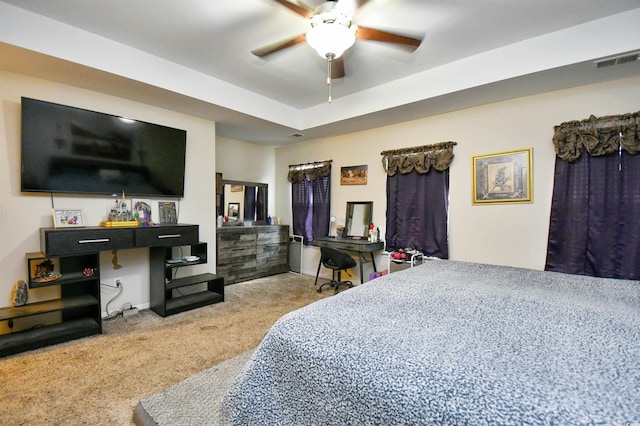 bedroom with light carpet, ceiling fan, and a tray ceiling