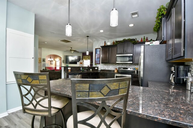 kitchen with a breakfast bar area, appliances with stainless steel finishes, kitchen peninsula, and hanging light fixtures