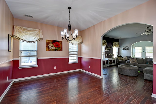 unfurnished dining area with dark wood-type flooring, a wealth of natural light, and ceiling fan with notable chandelier