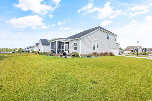 rear view of house with a garage, a lawn, and a sunroom