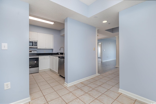 kitchen with white cabinetry, stainless steel appliances, sink, and light tile patterned floors