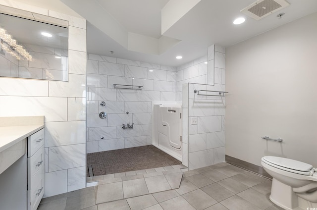 bathroom with vanity, tile patterned flooring, toilet, and tiled shower