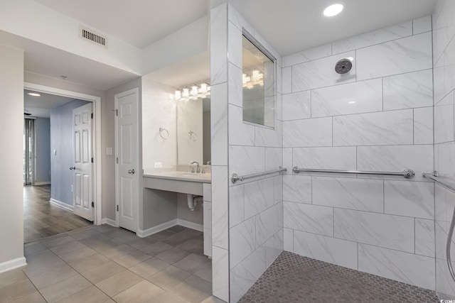 bathroom with tiled shower and hardwood / wood-style flooring