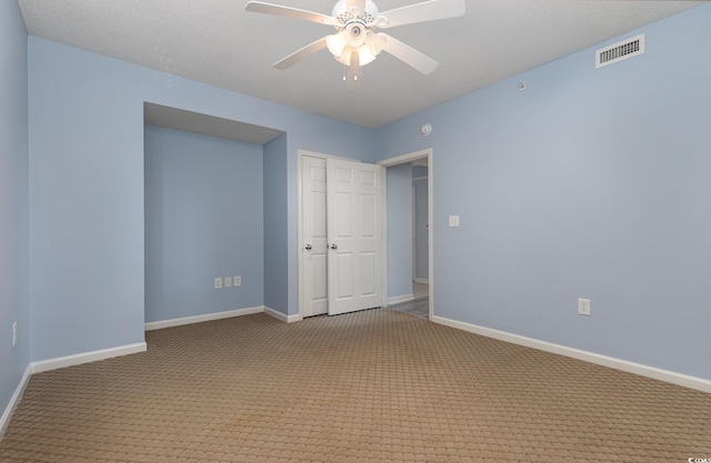 unfurnished bedroom featuring light carpet, a closet, a textured ceiling, and ceiling fan