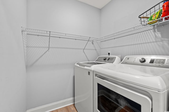 clothes washing area with washer and dryer and light hardwood / wood-style floors