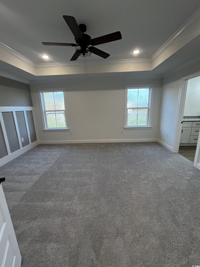 spare room with a raised ceiling, ceiling fan, carpet floors, and ornamental molding