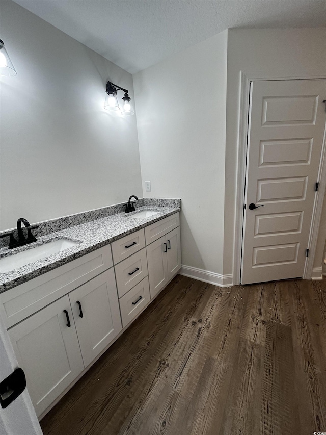 bathroom with wood-type flooring, vanity, and a textured ceiling