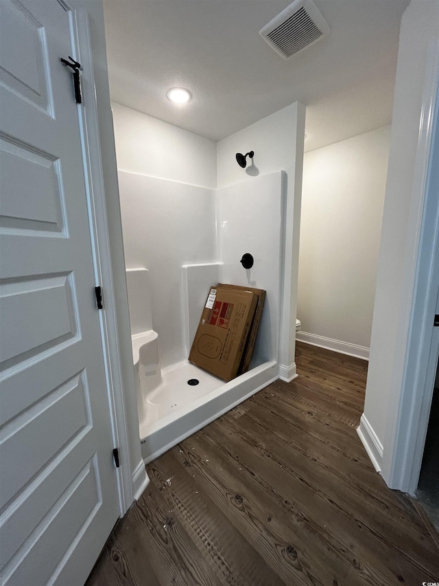 bathroom featuring hardwood / wood-style flooring, toilet, and walk in shower