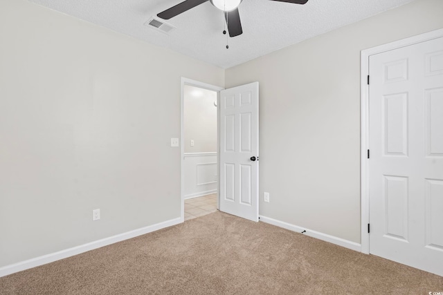 unfurnished room with light carpet, a textured ceiling, and ceiling fan