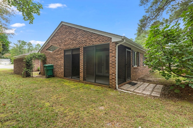 back of property with a sunroom and a lawn