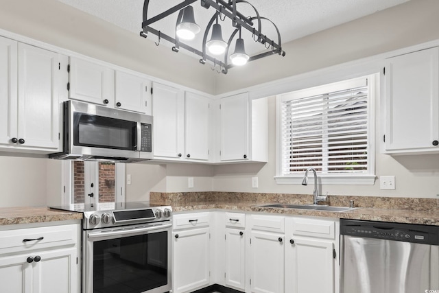 kitchen with appliances with stainless steel finishes, white cabinetry, sink, and a textured ceiling