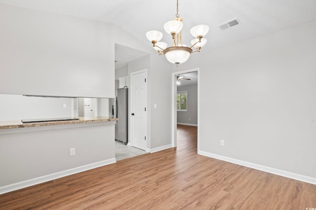 interior space featuring vaulted ceiling, light hardwood / wood-style flooring, a textured ceiling, and ceiling fan with notable chandelier