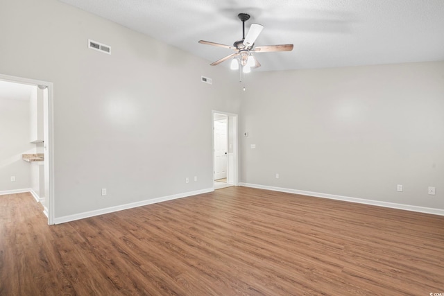 spare room featuring a textured ceiling, wood-type flooring, high vaulted ceiling, and ceiling fan