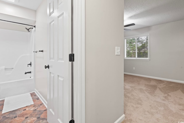 hall with a textured ceiling and light colored carpet