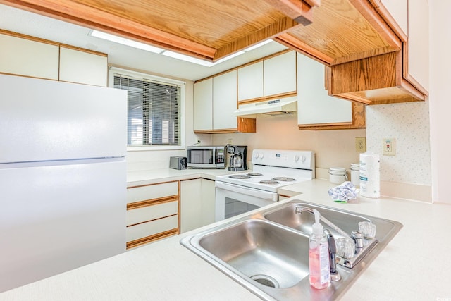 kitchen with white appliances, sink, and white cabinetry